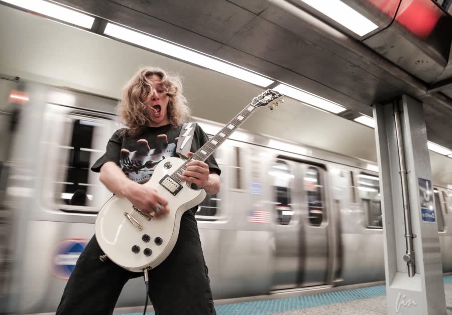 A guitarist performing in front of a moving train