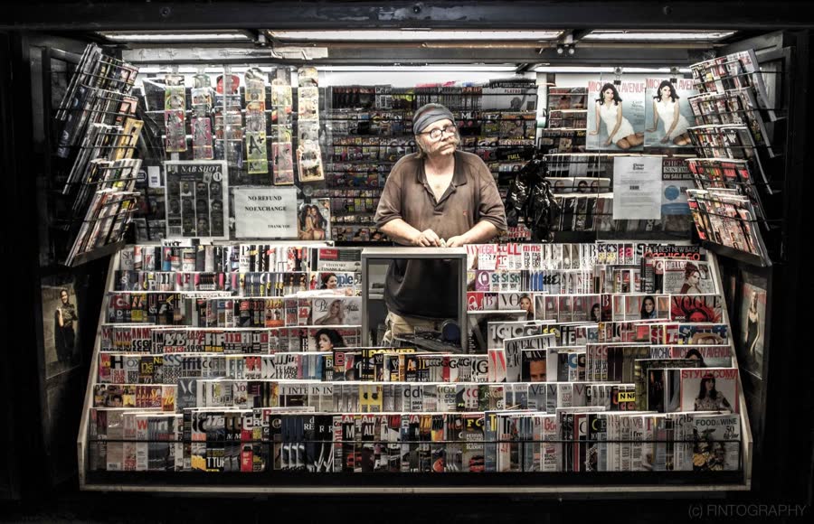 A magazine vendor standing inside a newsstand