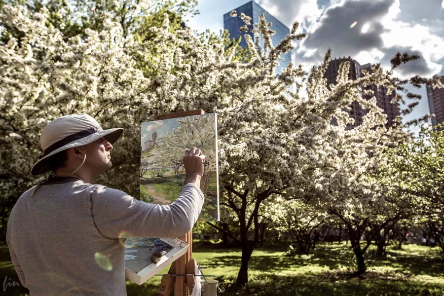 A painter working beneath flowering trees
